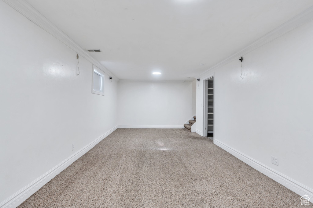 Basement featuring stairway, carpet, and crown molding