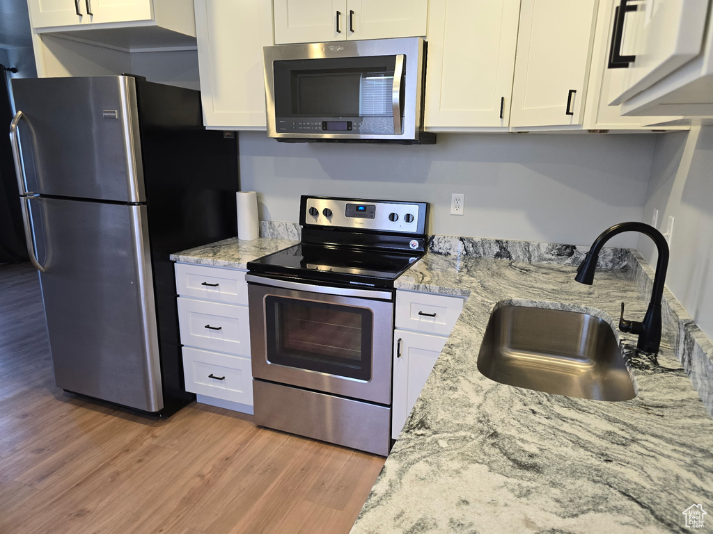 Kitchen featuring stainless steel appliances, light wood finished floors, and white cabinetry