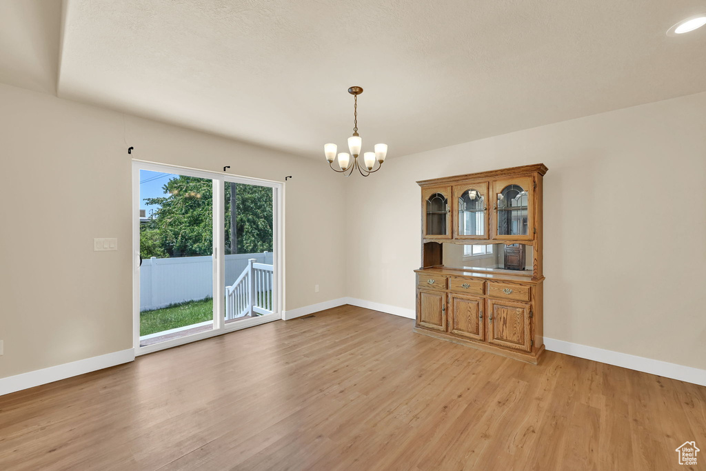 Empty room featuring a chandelier and light wood-style floors