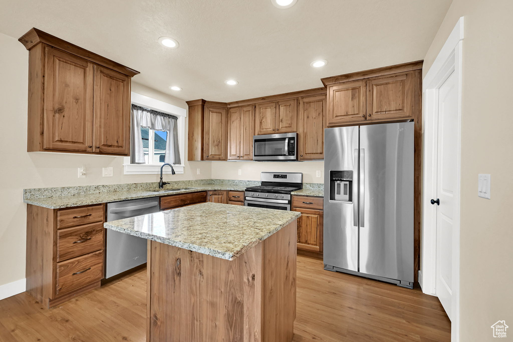 Kitchen featuring stainless steel appliances, light wood-style floors, light stone counters, recessed lighting, and brown cabinetry