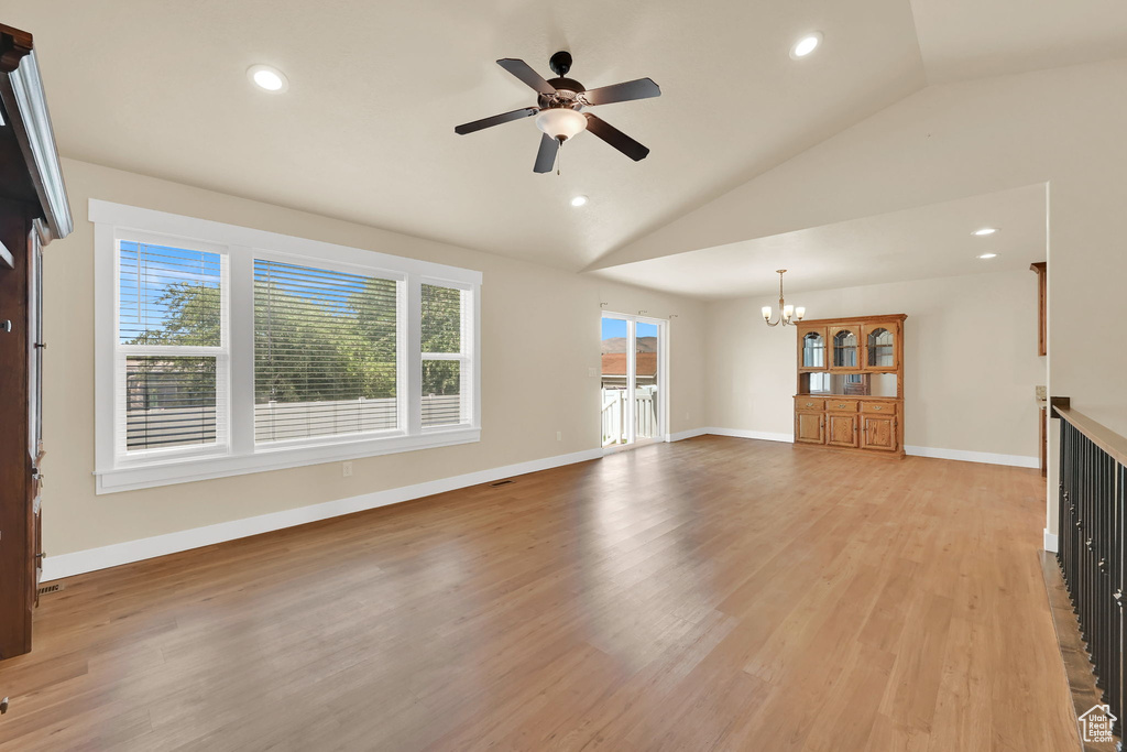 Unfurnished living room featuring a chandelier, plenty of natural light, ceiling fan, vaulted ceiling, and recessed lighting