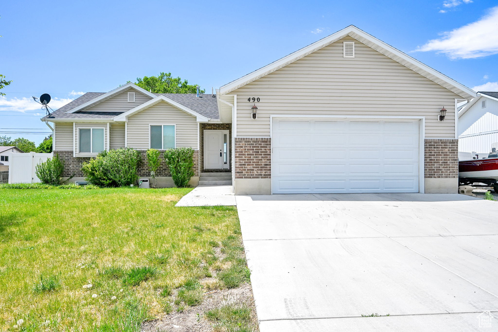 Ranch-style house with brick siding, driveway, a front lawn, and a garage
