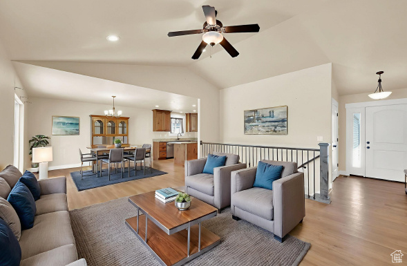 Living area with light wood-type flooring, lofted ceiling, ceiling fan, a chandelier, and recessed lighting