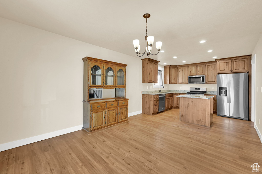 Kitchen featuring appliances with stainless steel finishes, light wood-style floors, a chandelier, recessed lighting, and decorative light fixtures