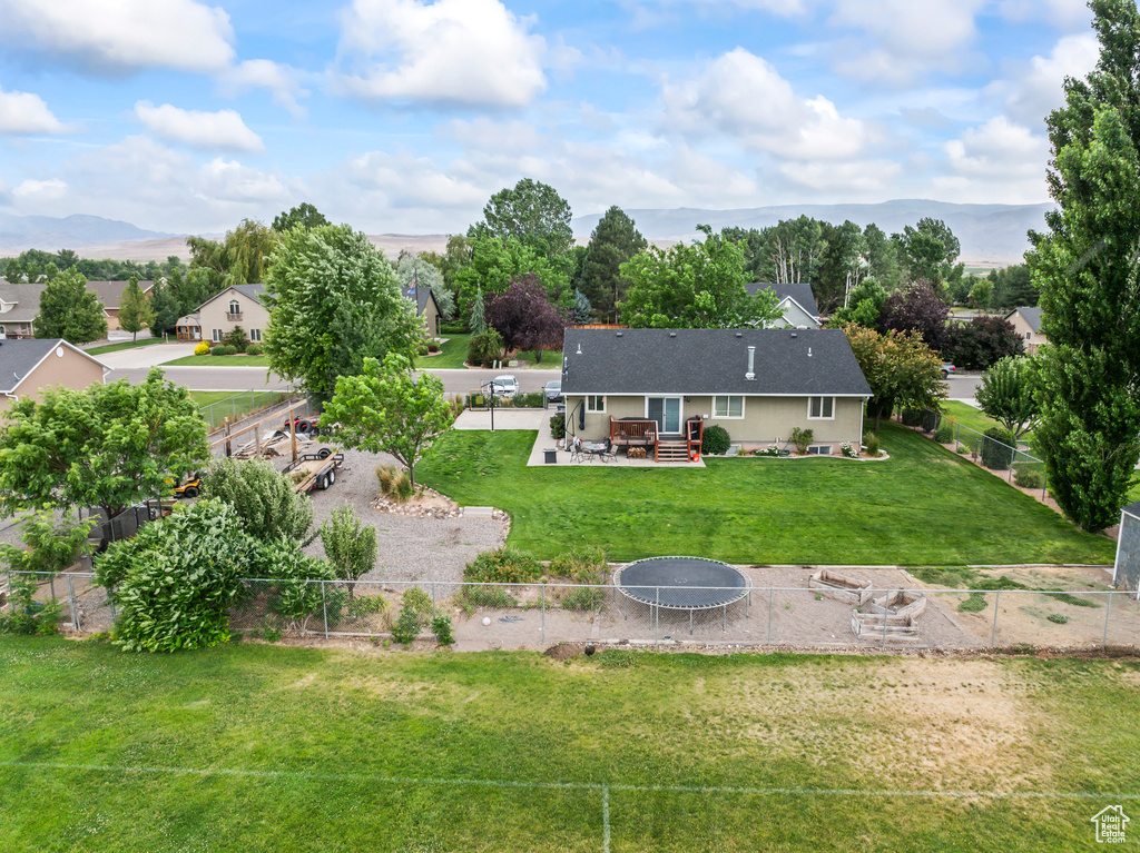 Rear view of property with a trampoline, a fenced backyard, and a patio