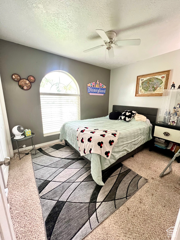 Bedroom with carpet floors, ceiling fan, and a textured ceiling