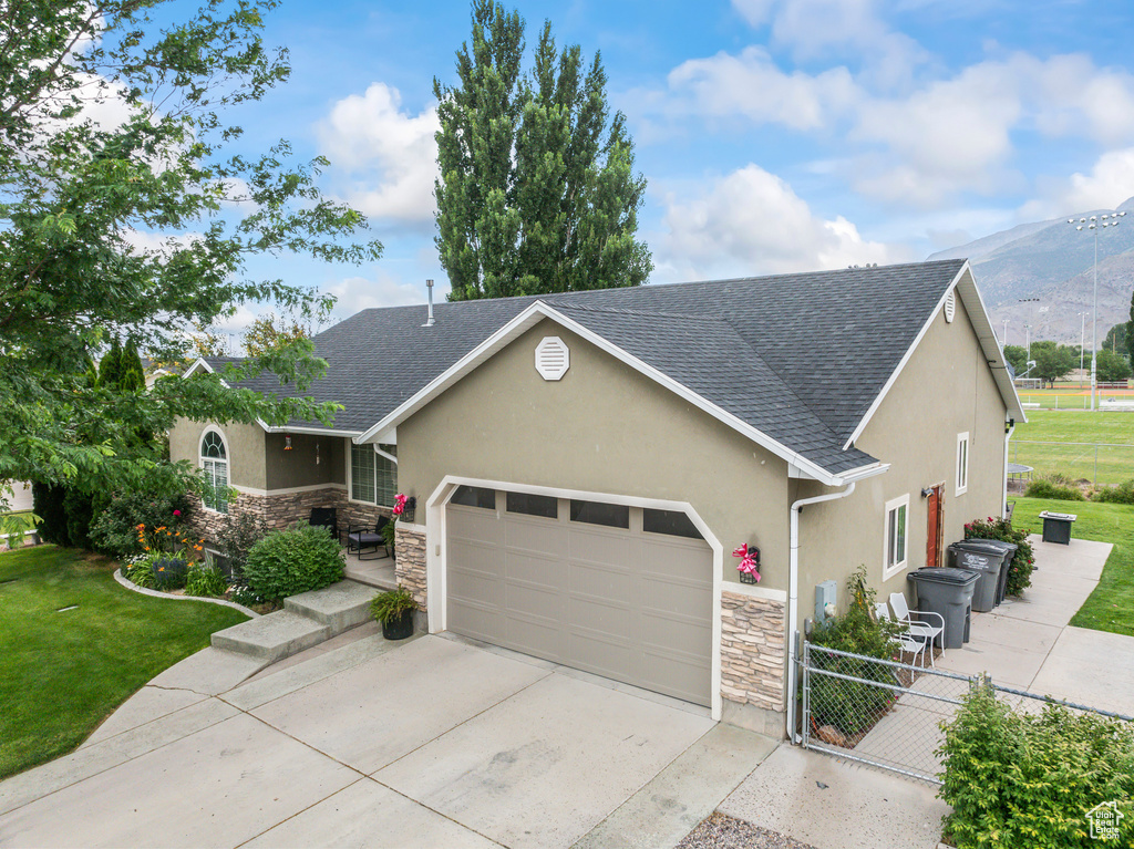 View of front facade featuring stone siding, concrete driveway, an attached garage, and stucco siding