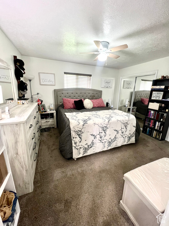 Bedroom with dark carpet, a textured ceiling, a closet, and a ceiling fan