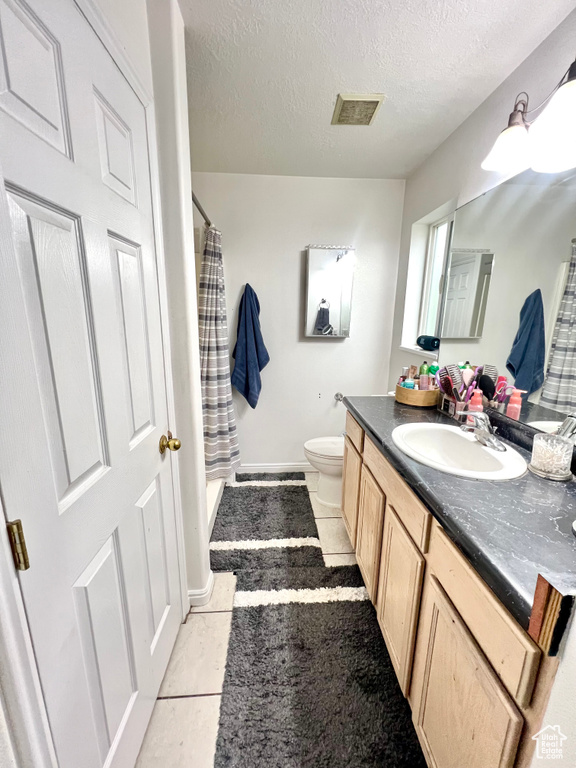 Bathroom with vanity, a textured ceiling, a shower with shower curtain, and tile patterned flooring