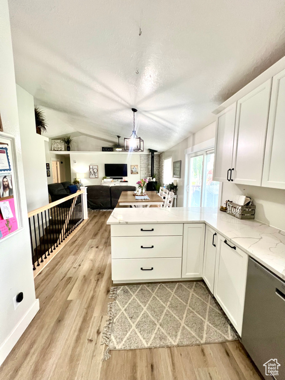 Kitchen with a wood stove, a peninsula, open floor plan, dishwasher, and light wood-style floors