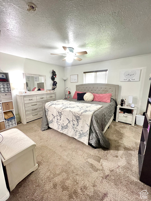 Bedroom with carpet, ceiling fan, and a textured ceiling