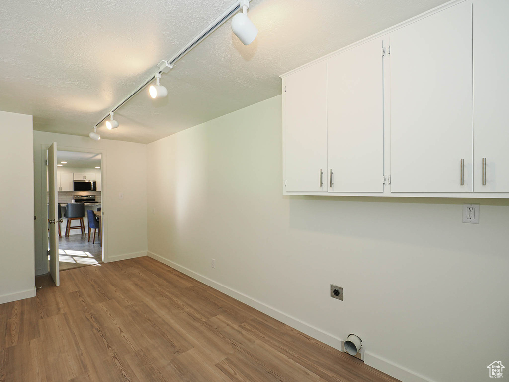 Spare room with rail lighting, wood finished floors, and a textured ceiling