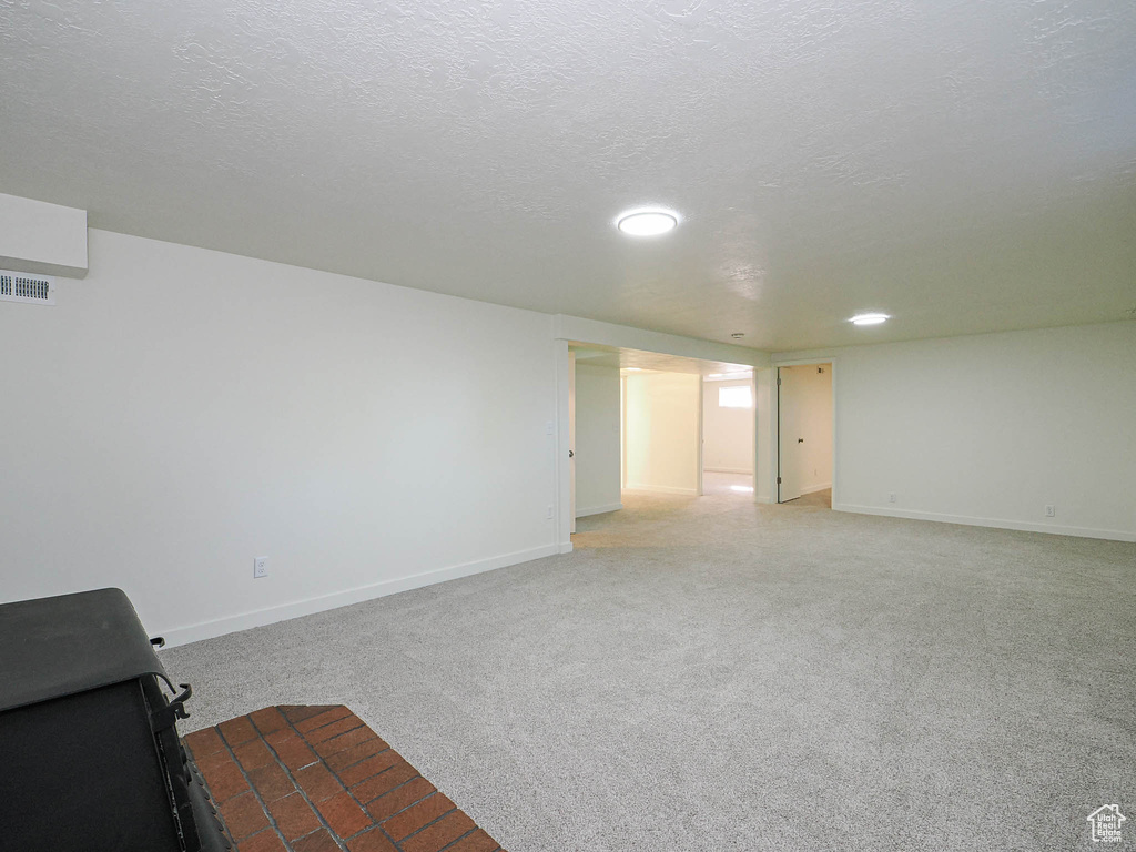 Unfurnished living room with light carpet, a textured ceiling, and recessed lighting