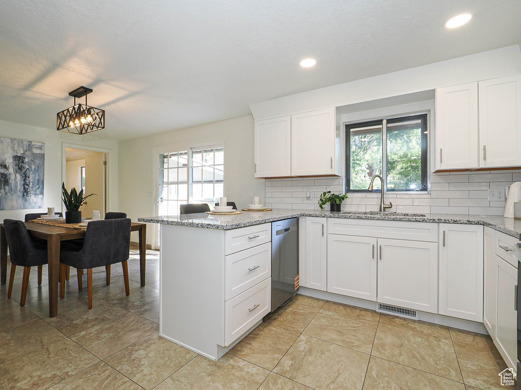 Kitchen featuring dishwasher, a peninsula, backsplash, white cabinetry, and recessed lighting