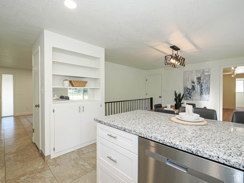 Kitchen with dishwasher, a chandelier, white cabinets, and a textured ceiling