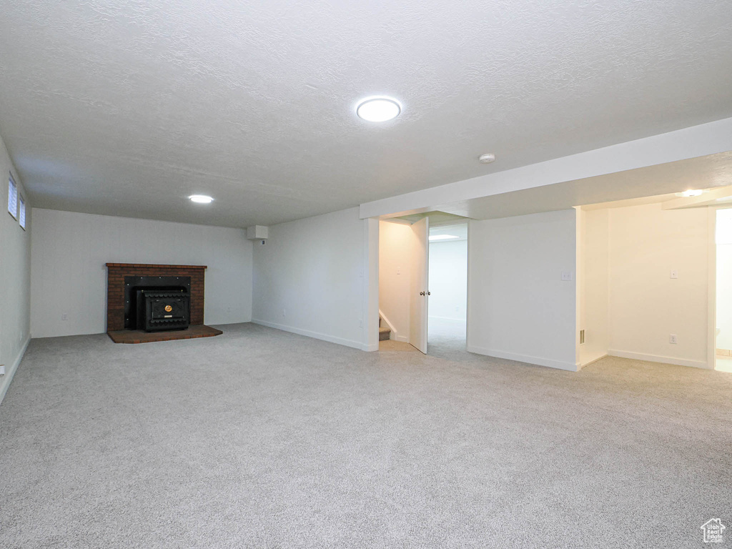 Unfurnished living room with a textured ceiling, light colored carpet, and stairway