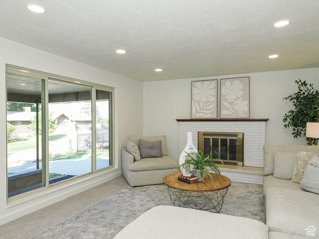 Living area with carpet flooring, recessed lighting, a textured ceiling, and a brick fireplace