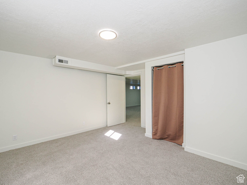 Unfurnished bedroom with a textured ceiling and light colored carpet