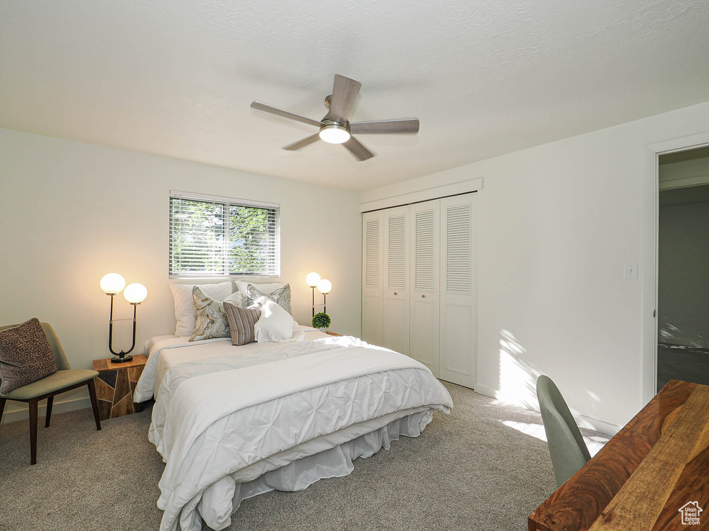 Bedroom with a closet, light colored carpet, and a ceiling fan