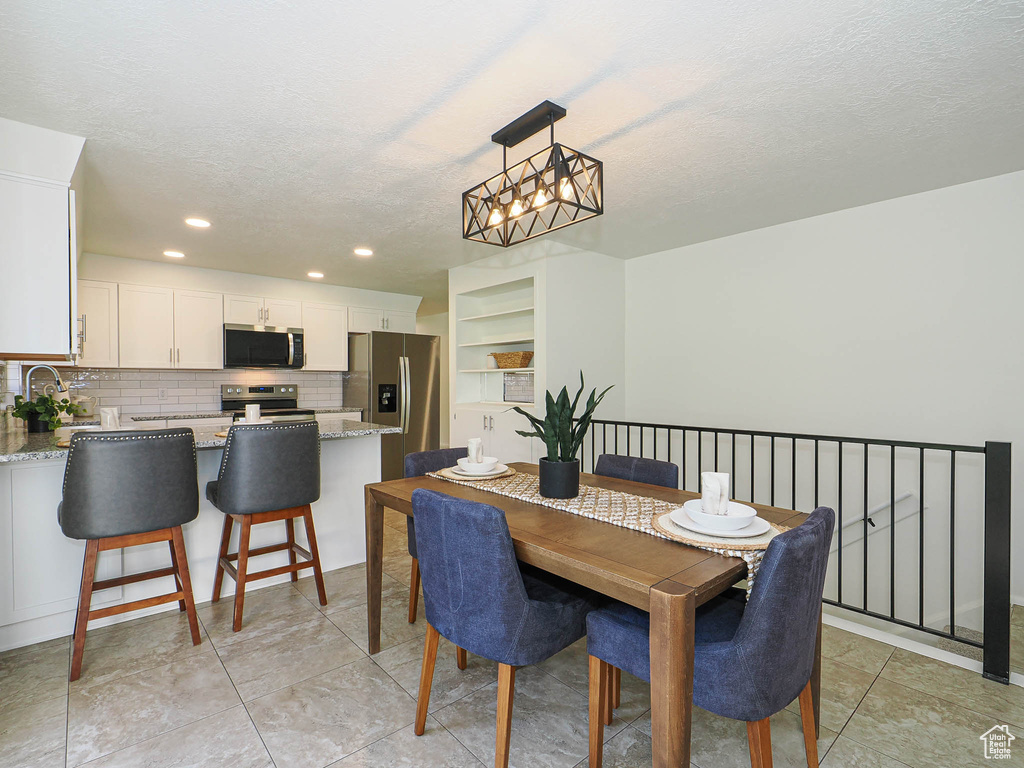 Dining area with a textured ceiling, recessed lighting, a chandelier, and light tile patterned floors