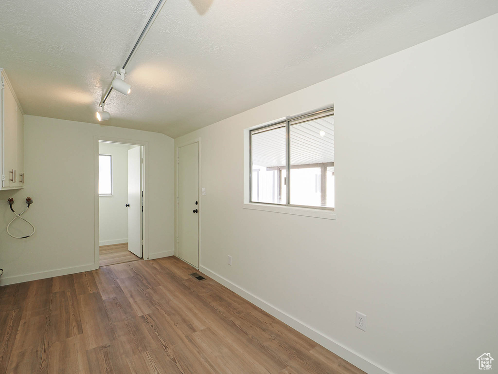 Unfurnished room featuring track lighting, wood finished floors, and a textured ceiling