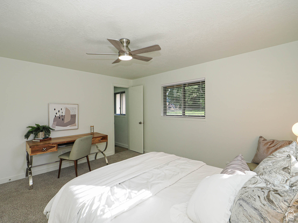 Bedroom with carpet flooring, ceiling fan, and a desk