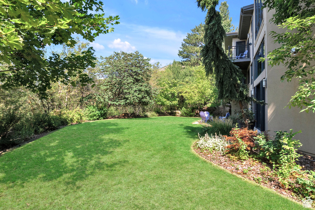 View of grassy yard with a balcony