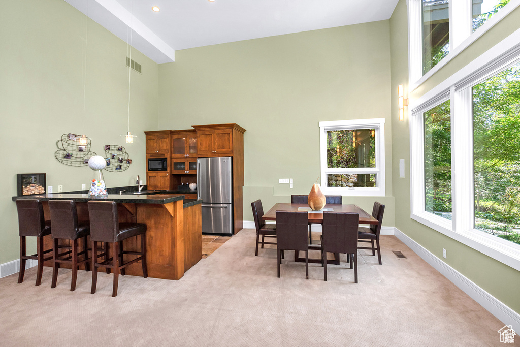 Dining space featuring a towering ceiling and light colored carpet