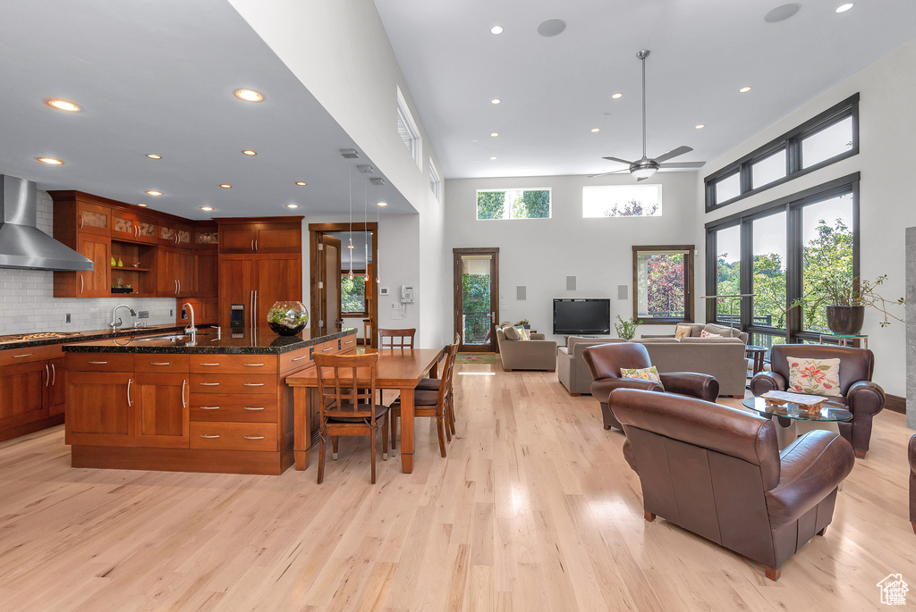 Kitchen featuring wall chimney exhaust hood, light wood-style flooring, open floor plan, healthy amount of natural light, and recessed lighting