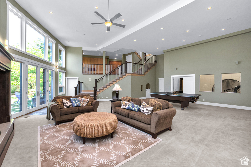 Living room featuring a high ceiling, carpet floors, stairway, billiards, and plenty of natural light