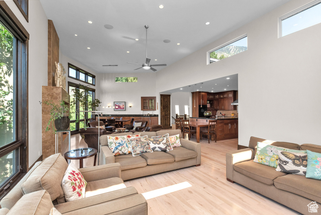 Living area with a high ceiling, light wood-style floors, recessed lighting, and ceiling fan