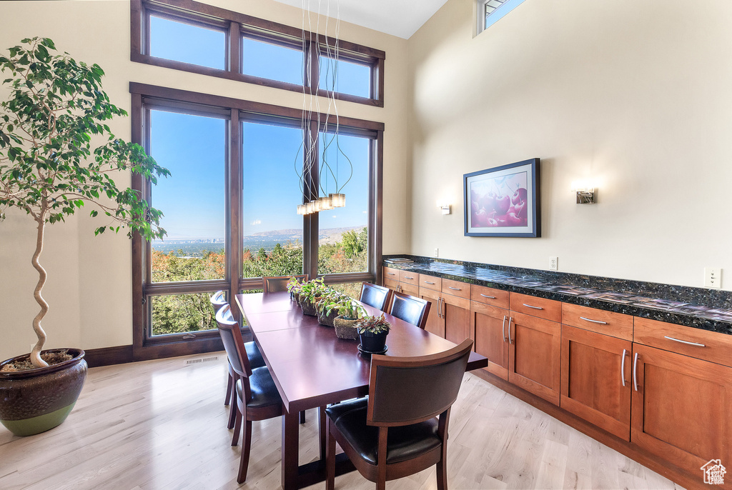 Dining room featuring light wood-style flooring and a towering ceiling