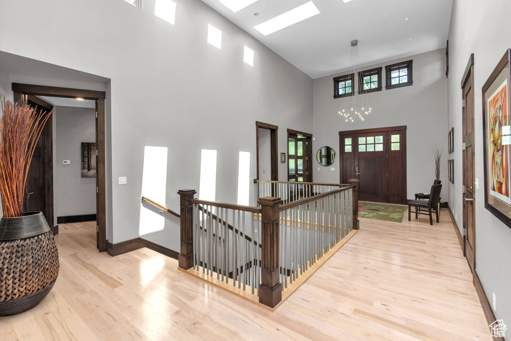 Foyer entrance with wood finished floors, a towering ceiling, and a chandelier
