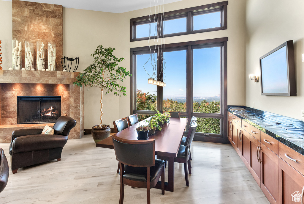 Dining room with light wood finished floors, a fireplace, and a towering ceiling