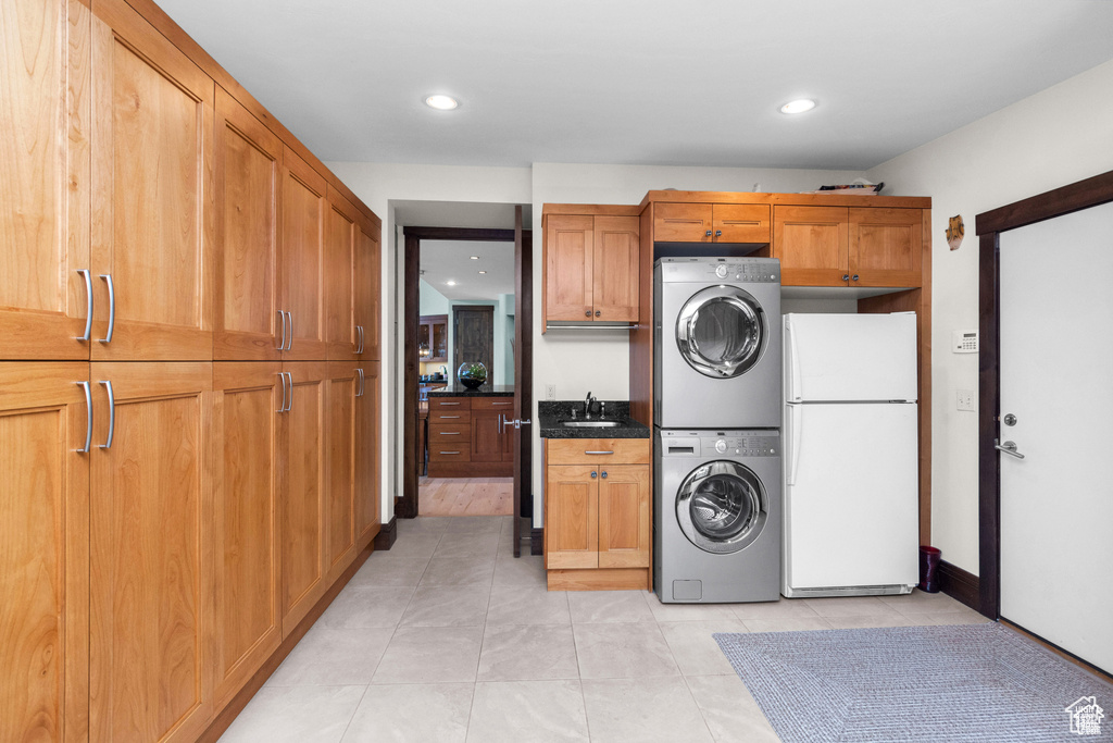 Washroom with stacked washer / dryer, cabinet space, light tile patterned floors, and recessed lighting