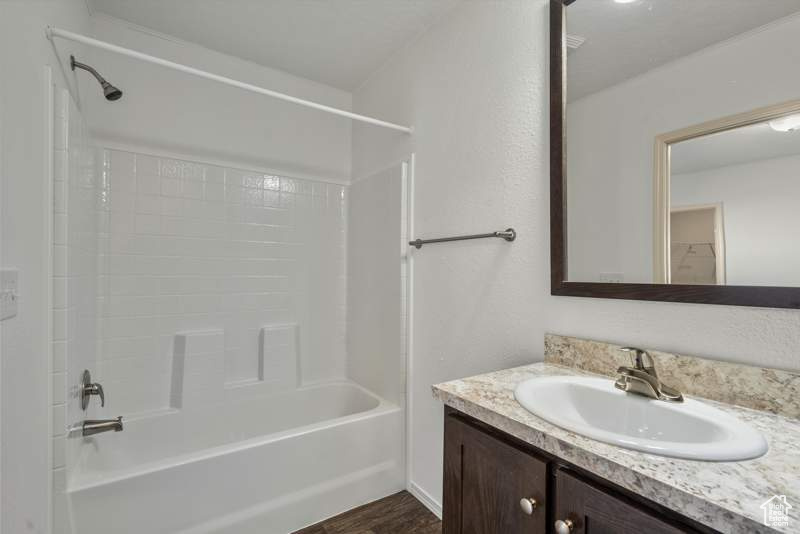 Full bathroom with vanity, washtub / shower combination, and wood finished floors