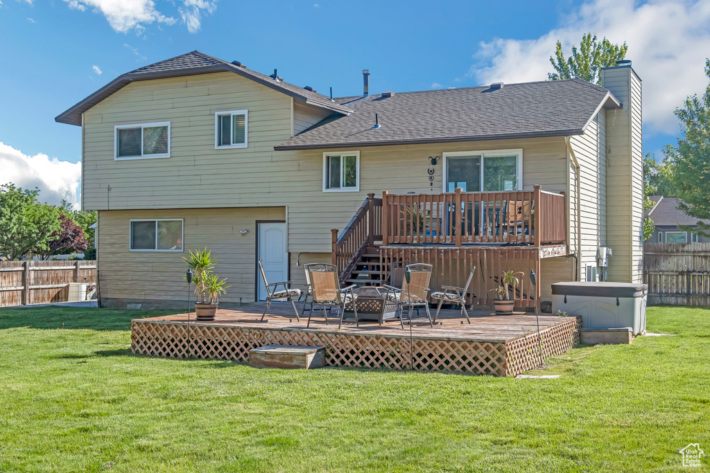 Rear view of property featuring a deck, a chimney, and a shingled roof