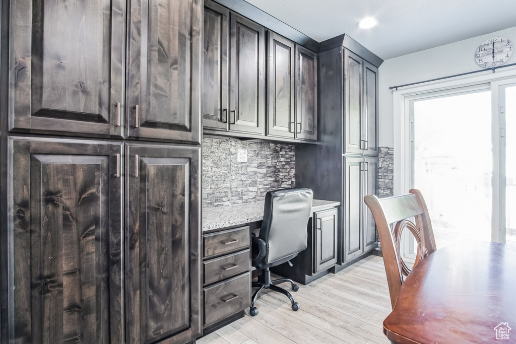 Office with light wood-style flooring and built in desk
