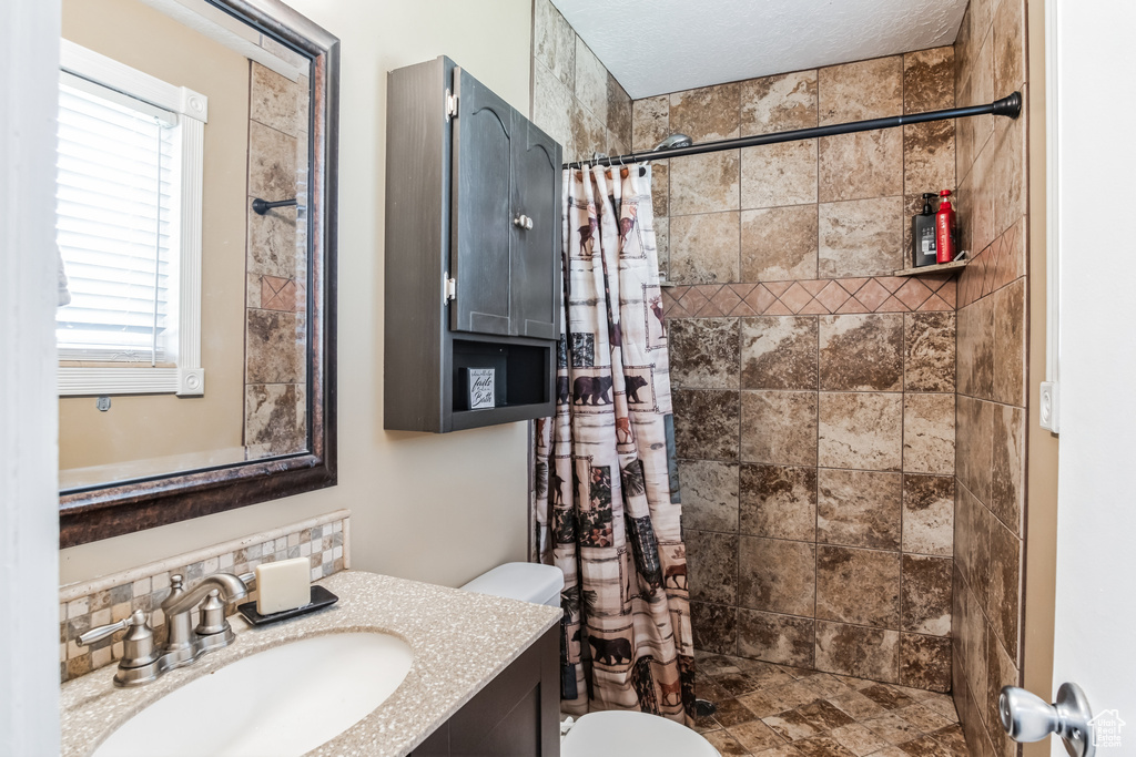 Bathroom with vanity, tiled shower, and decorative backsplash