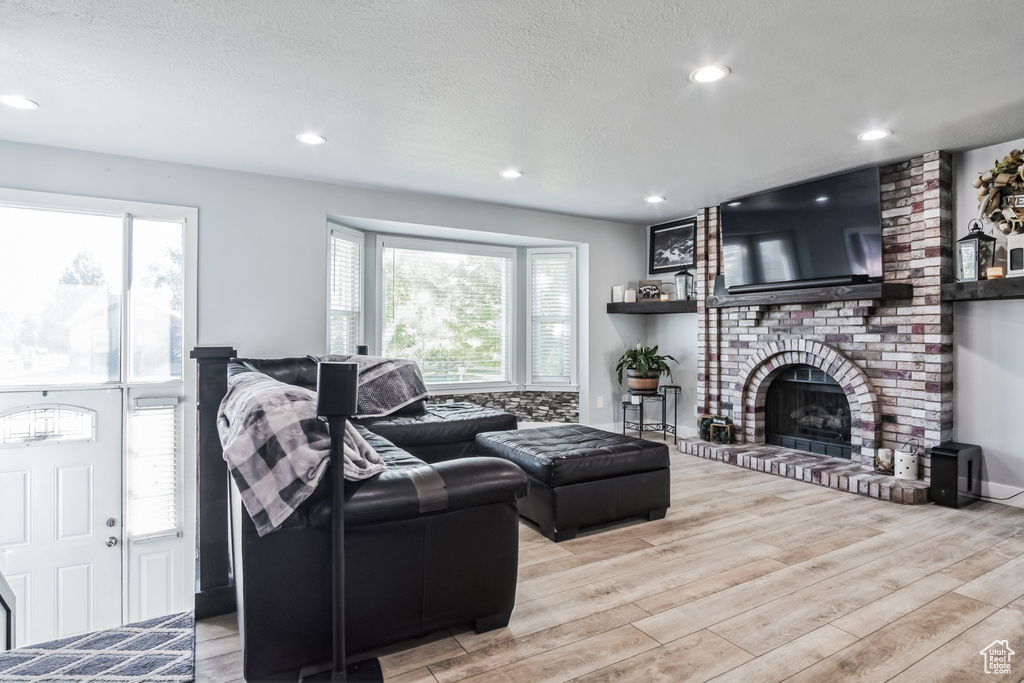 Living area with wood finished floors, a brick fireplace, recessed lighting, and a textured ceiling