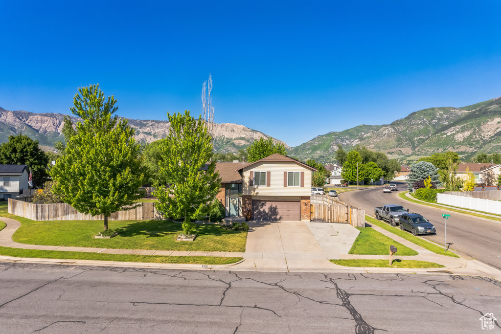 Split level home with a mountain view, driveway, an attached garage, and brick siding
