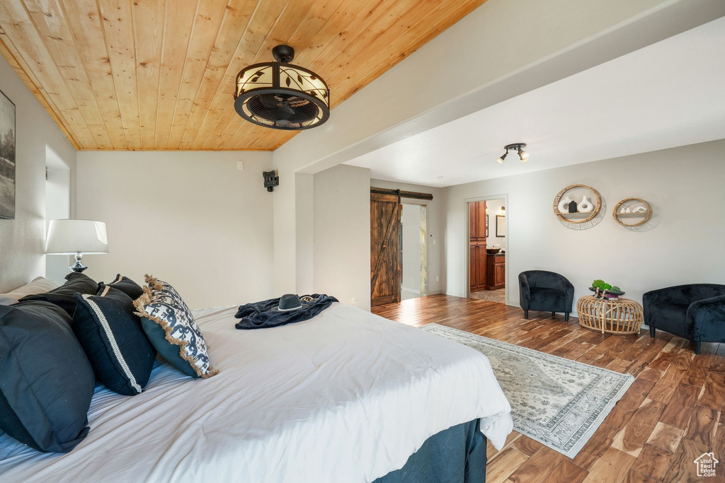 Bedroom with a barn door, wooden ceiling, wood finished floors, and ensuite bathroom