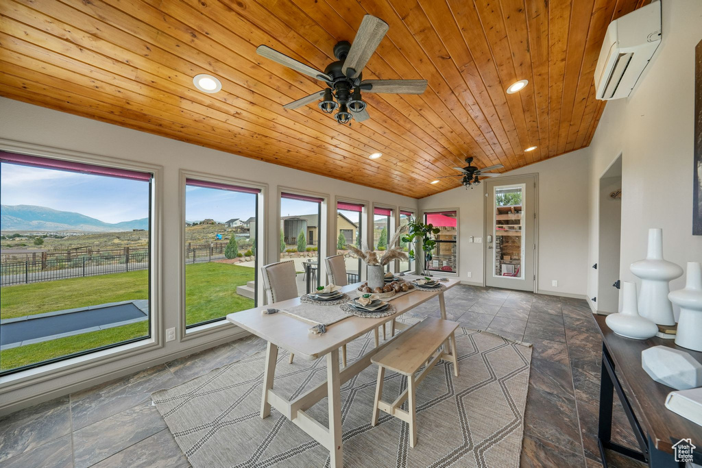 Sunroom / solarium featuring a wall mounted AC, lofted ceiling, and a mountain view