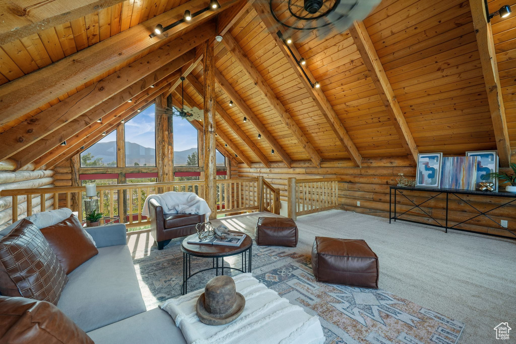 Living room featuring track lighting, wood ceiling, a mountain view, rustic walls, and carpet floors