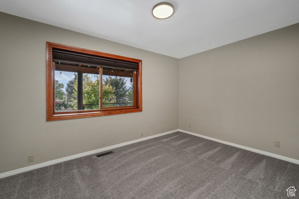 Empty room featuring dark colored carpet and baseboards