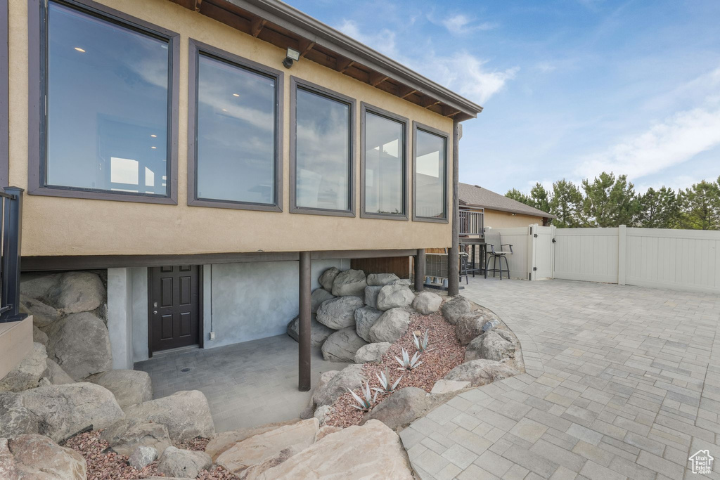View of property exterior featuring stucco siding, a patio, and a gate