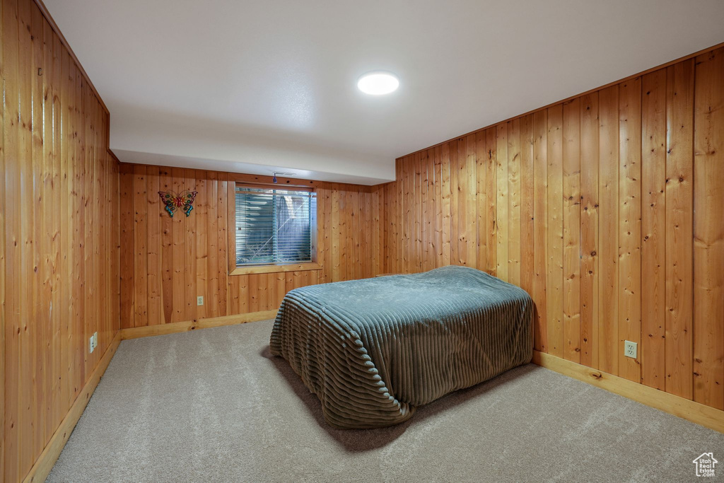 Bedroom with carpet floors and wood walls