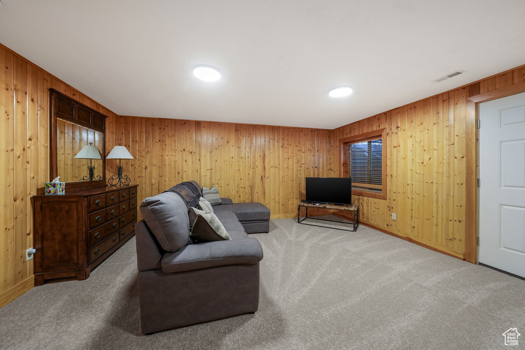 Carpeted living area featuring wooden walls