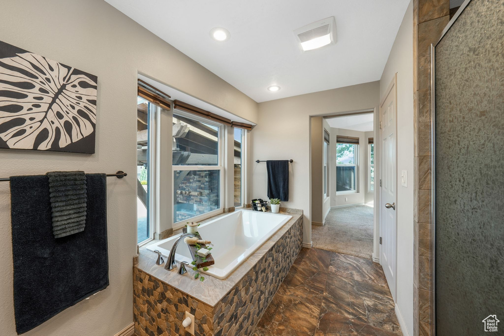 Bathroom featuring a bath, stone finish floors, and recessed lighting