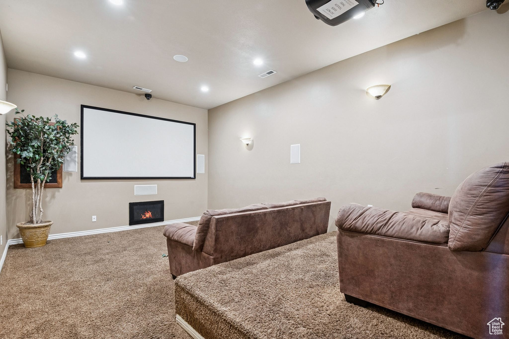 Carpeted home theater featuring recessed lighting and a lit fireplace